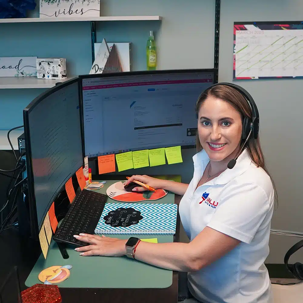 Our office manager at Value Painting and Flooring, shown at her workstation wearing headphones to take customer calls, emphasizing our commitment to exceptional customer service.