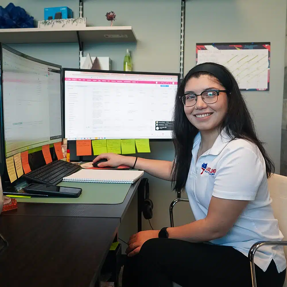 A female employee of Value Painting and Flooring, shown near her workstation with a computer and phone, ready to assist customers with their painting and flooring needs.